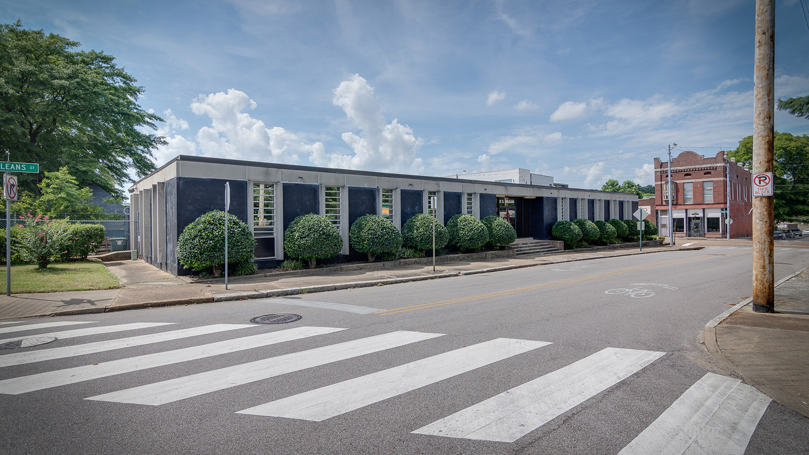 11 S Orleans Street, Memphis: a low building painted black with white concrete window fins and clipped boxwoods along the sidewalk.