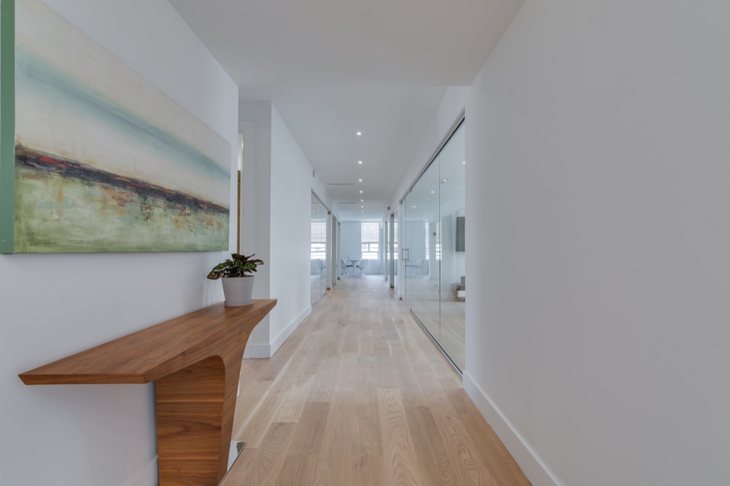 The corridor, with pale oak floors and glass office partitions